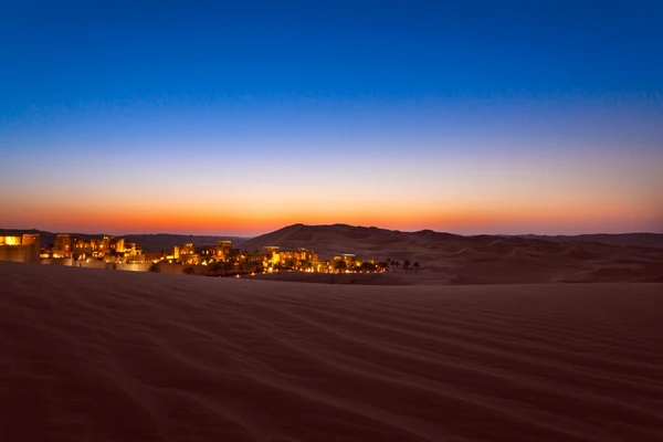 Lantern-lit private dinner setup in the desert under the evening sky