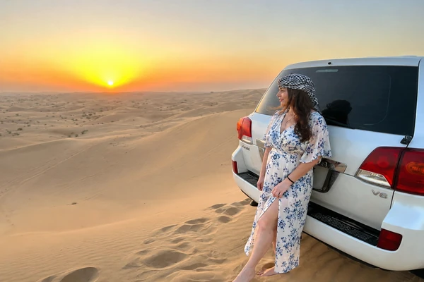 Traveller beside a four-wheel-drive vehicle at sunset in the Abu Dhabi desert