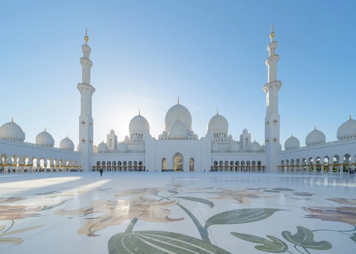 Traveller walking towards Sheikh Zayed Grand Mosque at golden hour