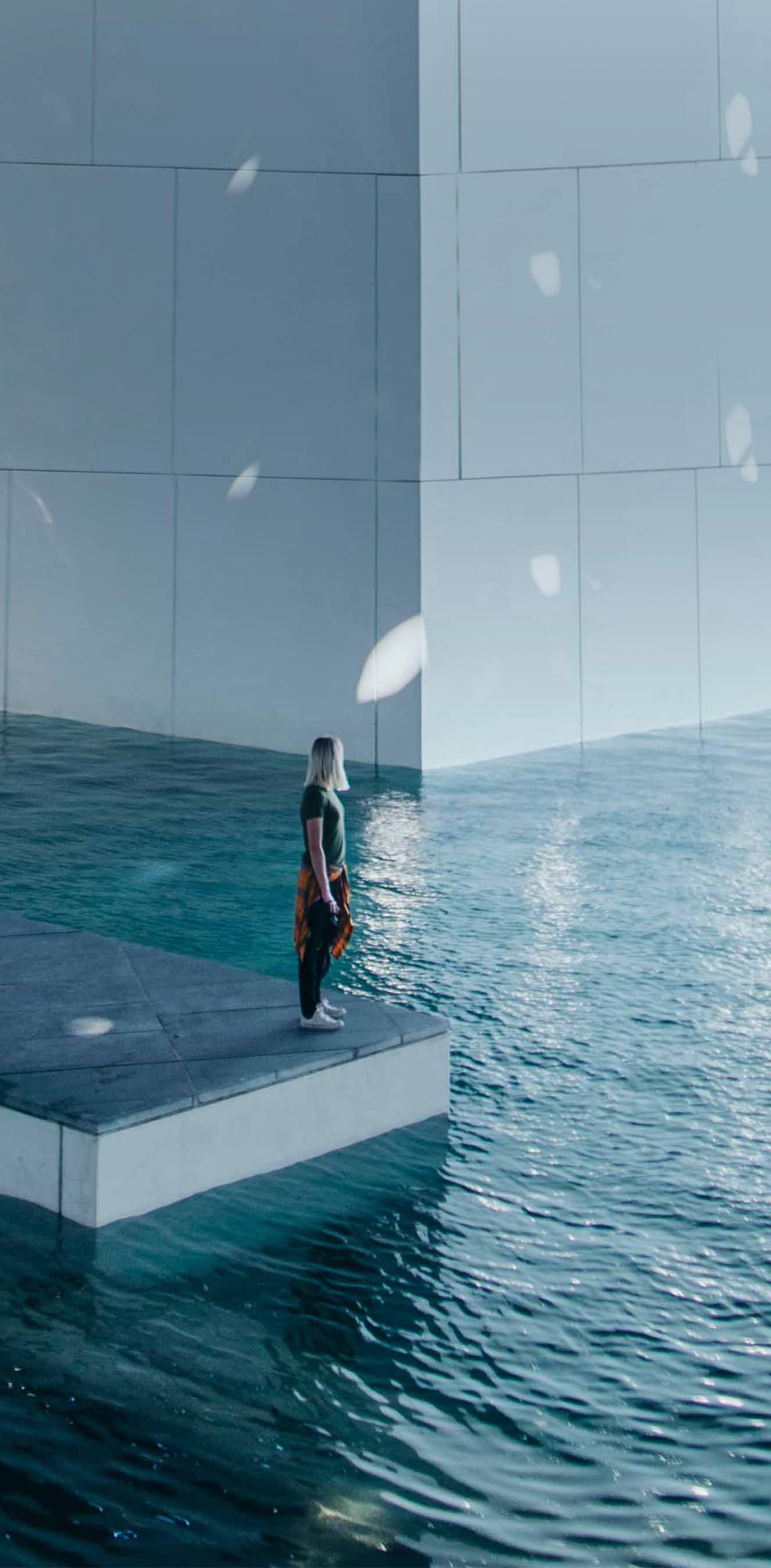 A visitor stands on a walkway surrounded by water at the Louvre Abu Dhabi